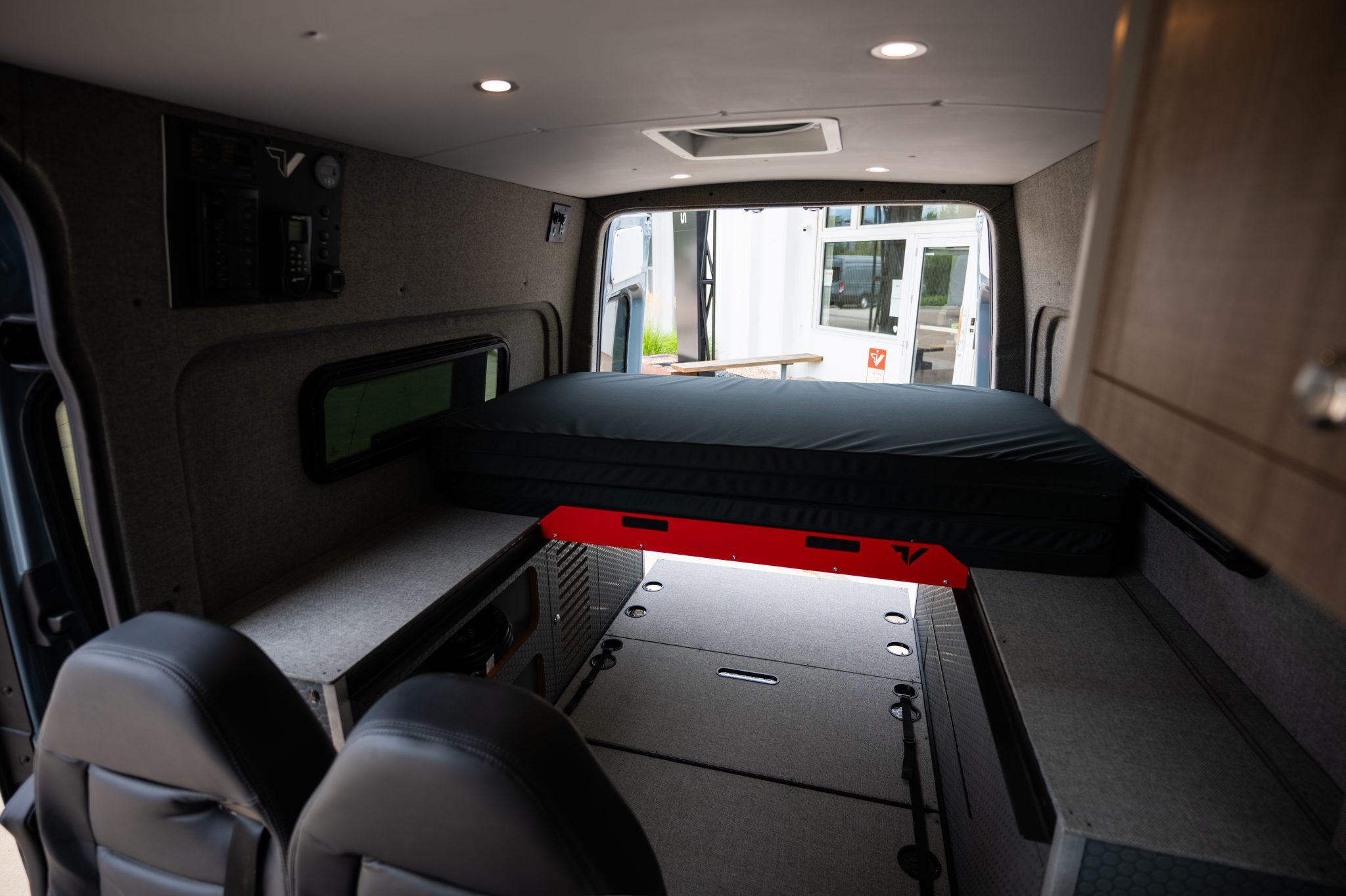 Camper van interior looking rear at the bi-slide bed and adventure floor